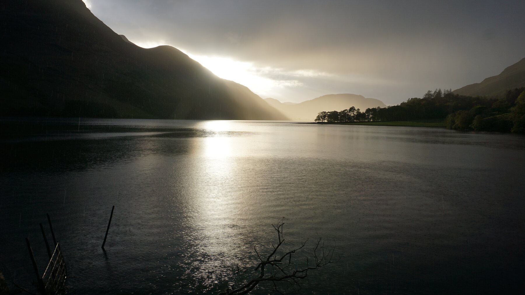 Sun breaking through dark mountains over Buttermere in the Lake District