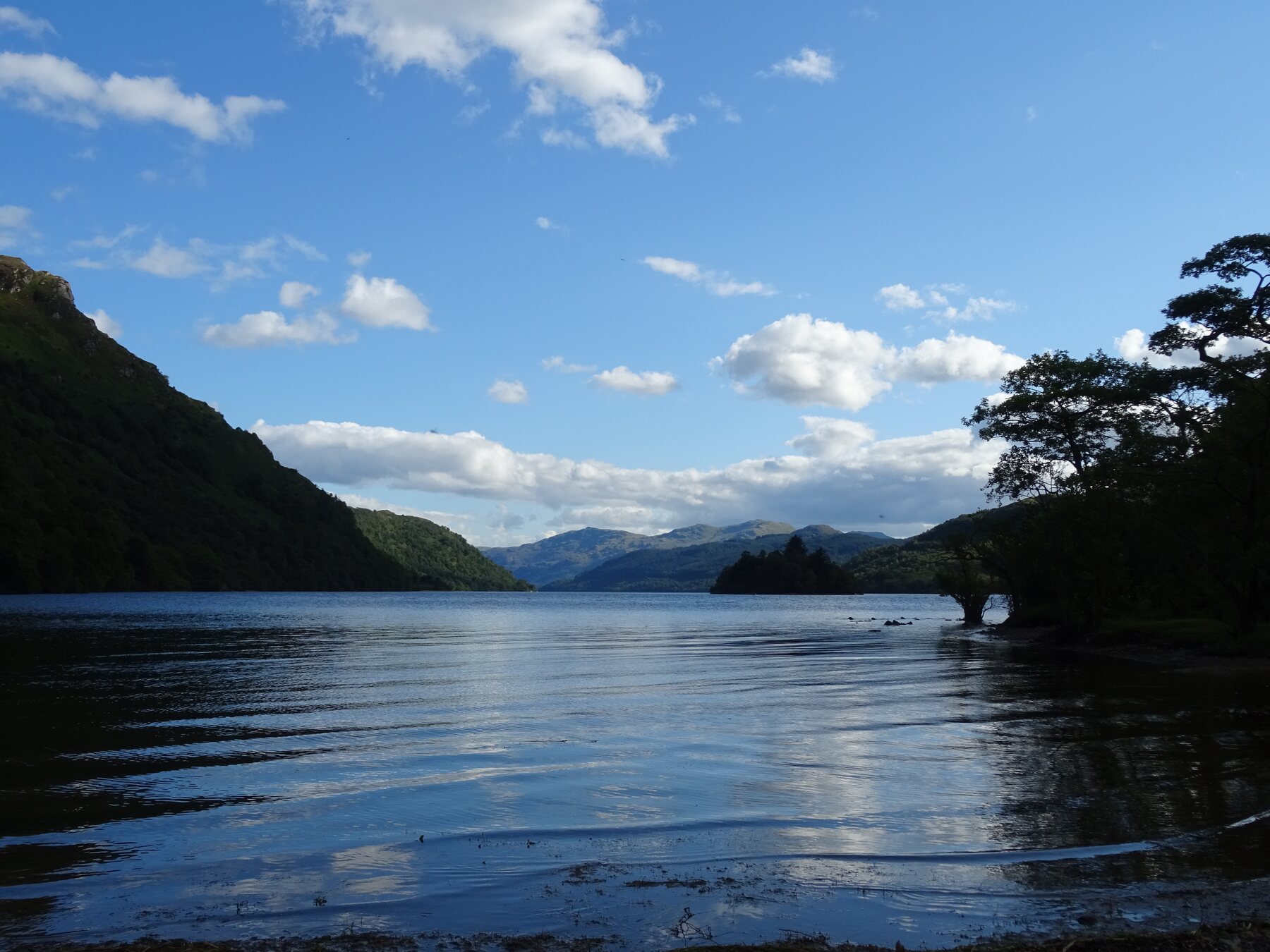 View across Loch Lomond towards wooded islands and distant Scottish mountains